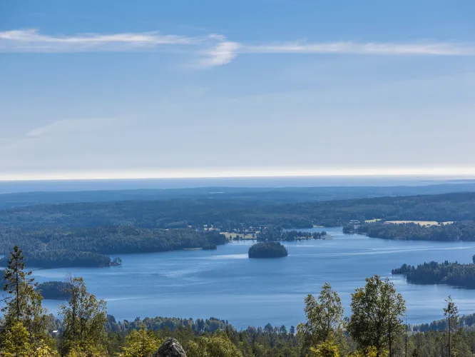 Utsikt från bergshöjd över sjö och skogar.