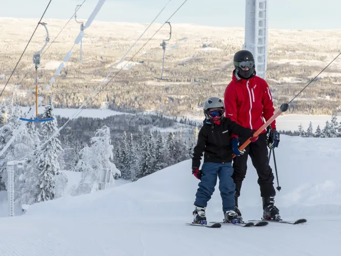 Färgbild - skidåkare i skidlift med vinterlandskap i bakgrunden