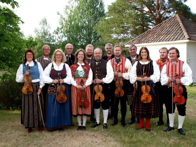 Gruppbild på alla spelmän och kvinnor - utomhus i grönskan