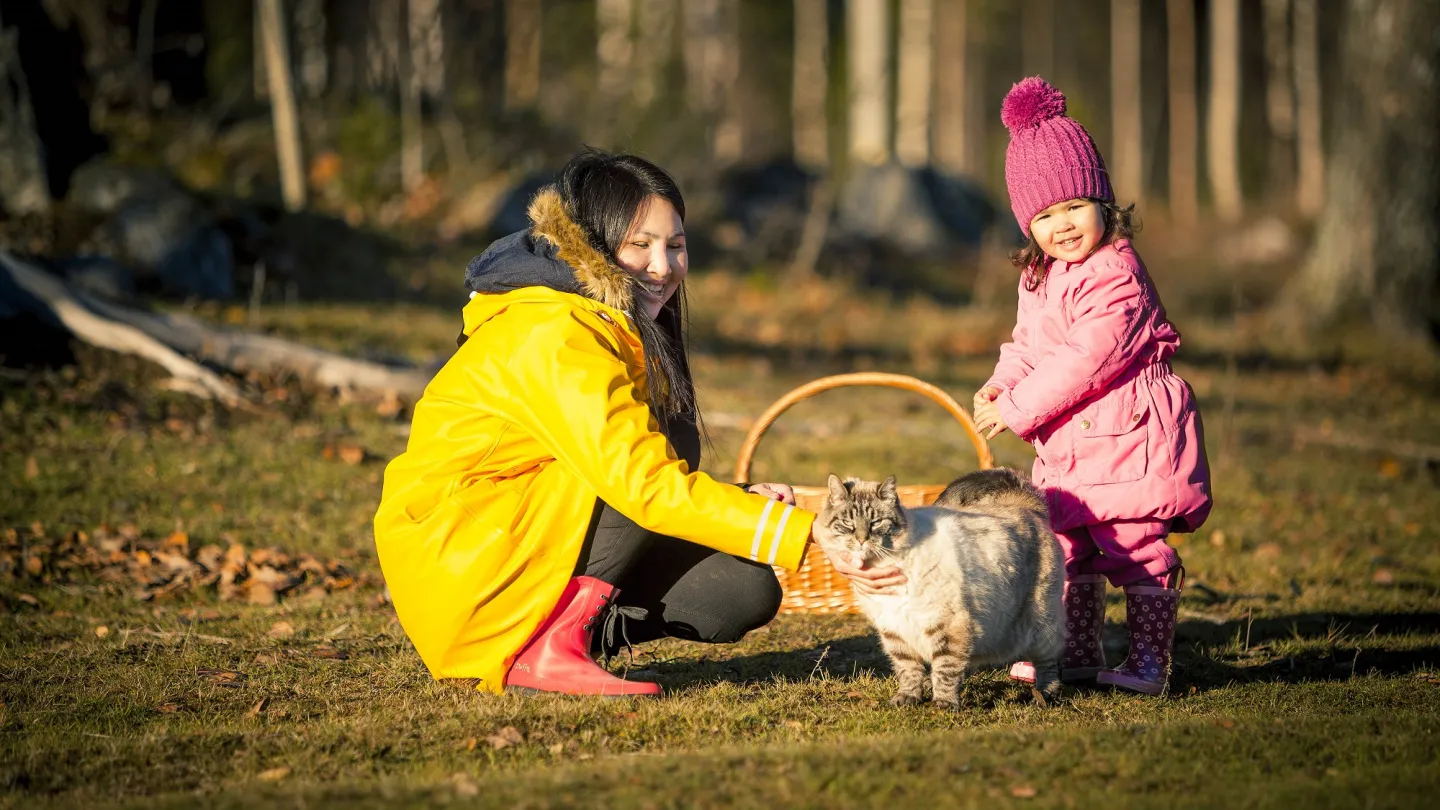 Kvinna med barn och en katt ute i naturen