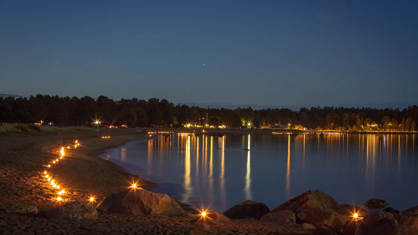 Lyskväll - Strand i skymningen med tända marschaller