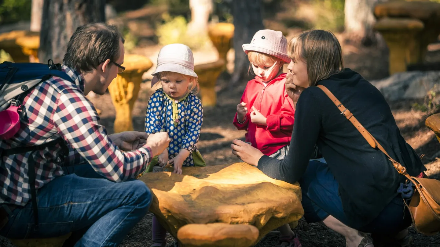 Familj sittande på huk i Trolska Skogen