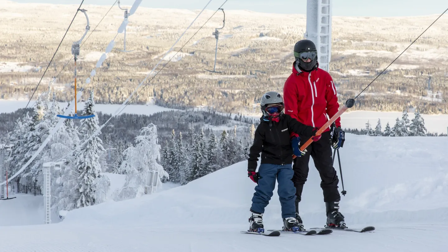 Färgbild - skidåkare i skidlift med vinterlandskap i bakgrunden