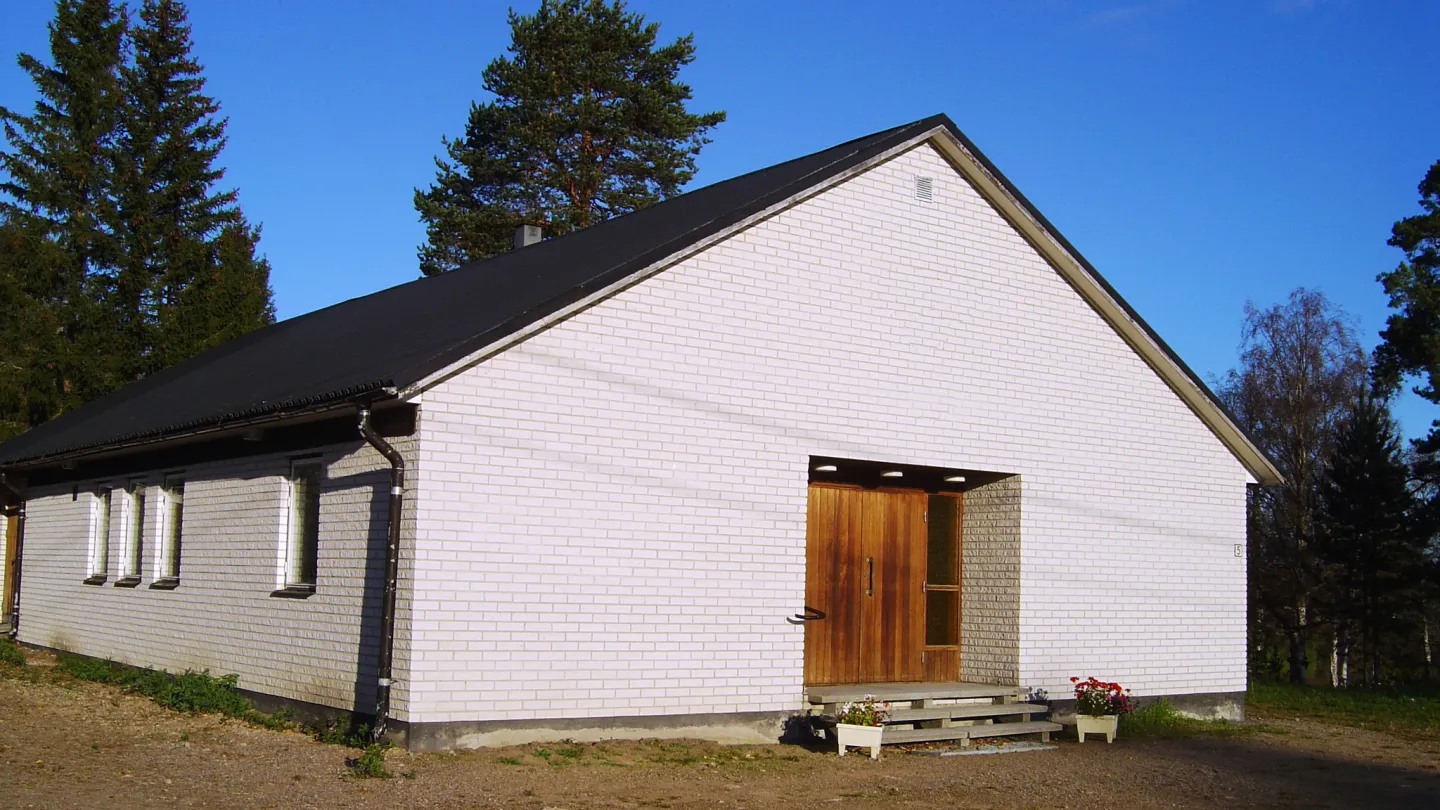 Vitt tegelhus med brun entredörr.