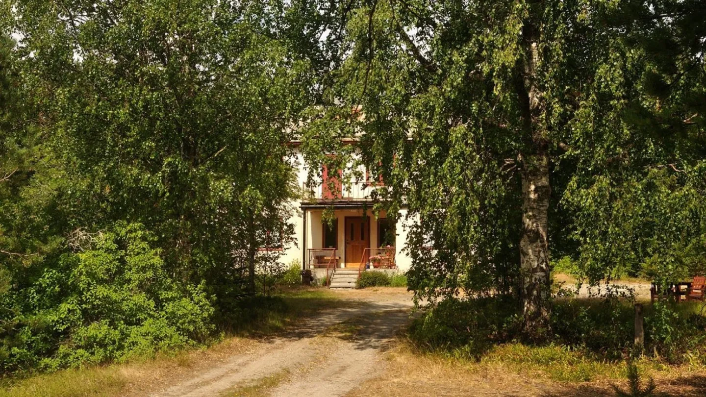 Lövträdsallé på väg till ett anande hus med brokvist