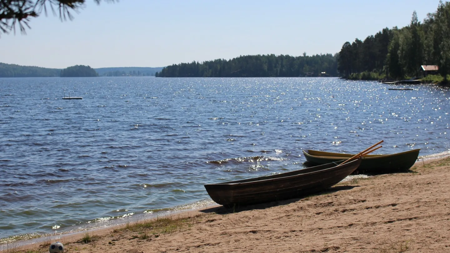 Två roddbåtar vid strandkant med utsikt över sjö - Sagaliden camping