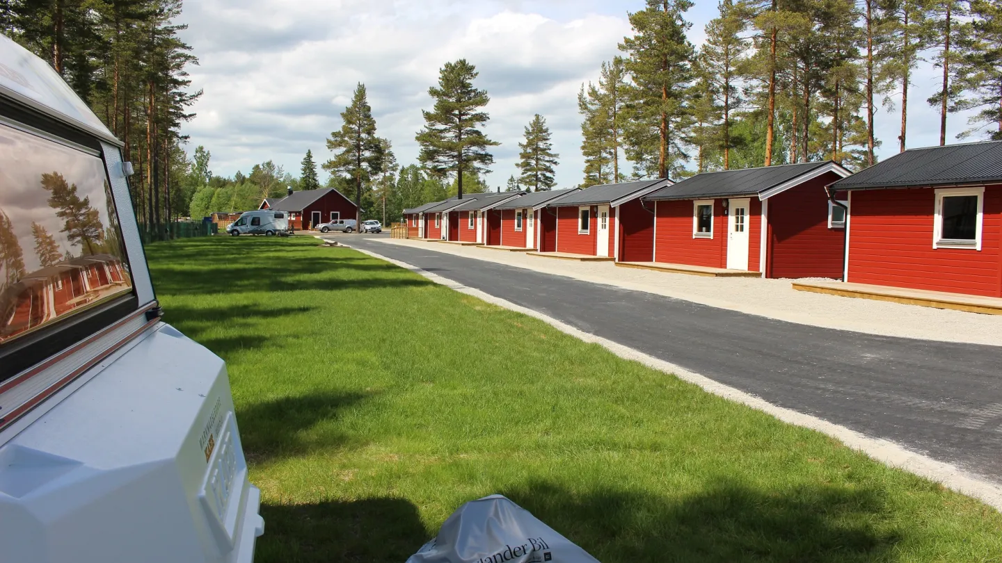 Stugor på rad i Sörfjärden med husvagn i förgrunden.